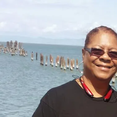 Barbara smiling by the water in her workout gear